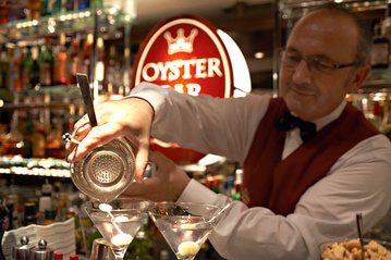[Translate to English:] Barkeeper mixt Martinis in der Oysterbar
